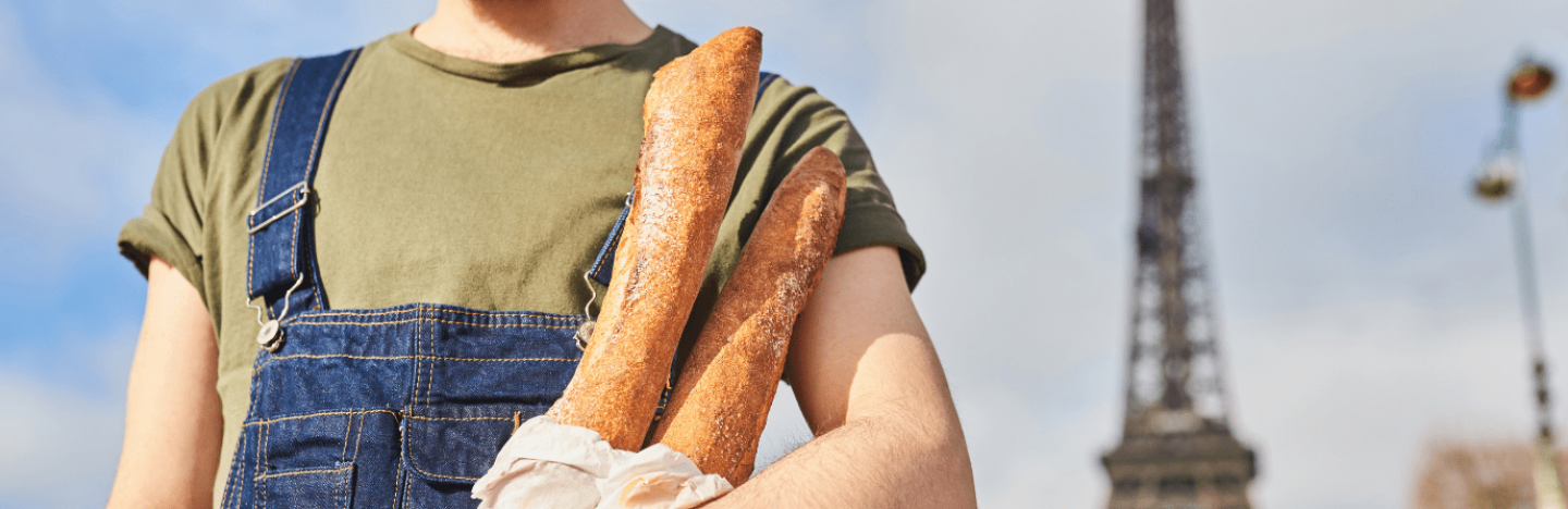 Homme français portant des baguettes de pains proche de la Tour Eiffel