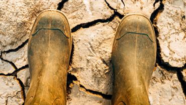 Bottes d'agriculteur dans un champ où la terre est sèche