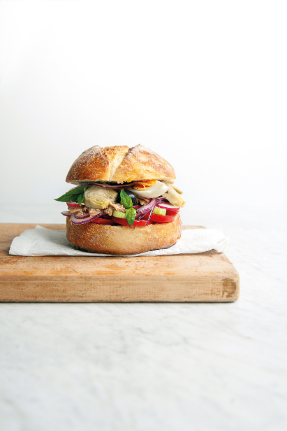 Pan-bagnat sandwich avec pain rond vue de côté, œufs, tomates et thon